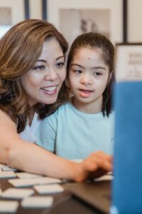 pexels-photo-7944382-7944382 An adult and young girl with Down syndrome smiling and bonding indoors.